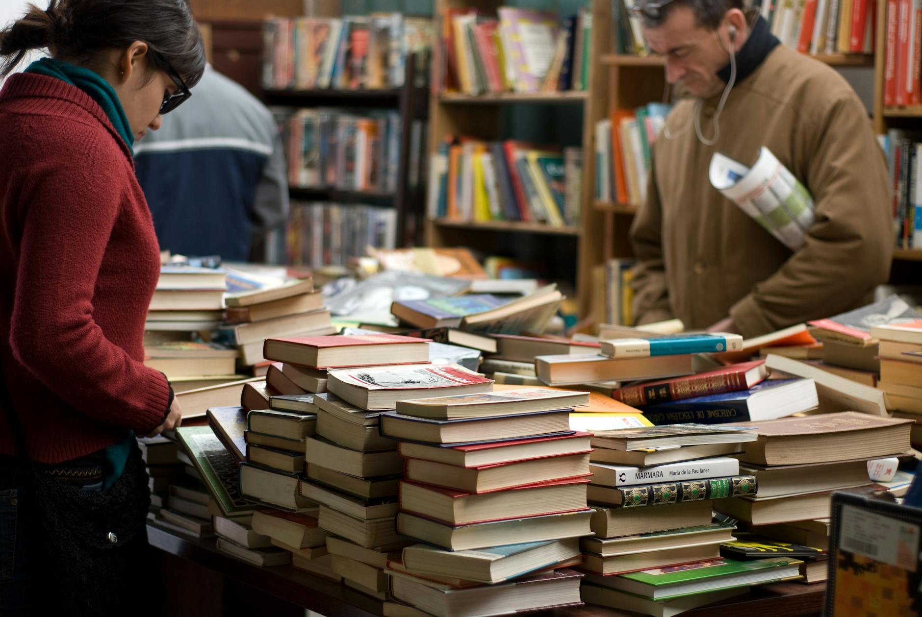 woman and man standing beside piles of books